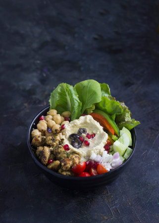 Lebanese-inspired falafel hummus bowl, served with salad and chickpeas on a black background.の写真素材