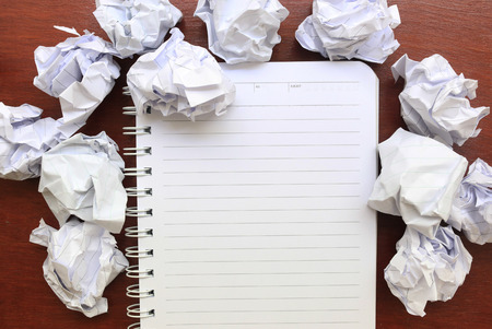 notebook paper with crumpled paper on wooden tableの写真素材