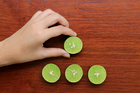 Hand holding half Lemon on wood table background, top viewの写真素材