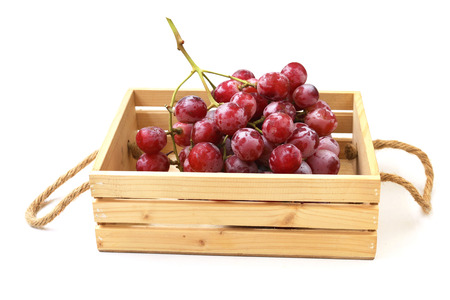 Red grape in a wooden crate on white background.の写真素材