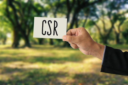 Hand holding a paper card with Corporate social responsibility (CSR) concept on abstract nature backgroundの写真素材