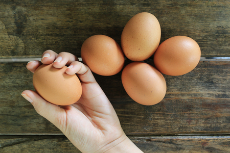 Hand Holding Eggs on wooden table backgroundの写真素材