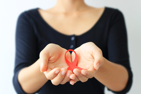 Aids Awareness. female hands holding red AIDS awareness ribbon.