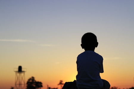 The silhouette of boy sitting alone, concept of lonely, sad, alone and scaredの写真素材