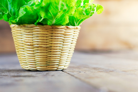 Fresh green lettuce salad in basket on wooden table background. vegetarian or healthy eating concept.の写真素材
