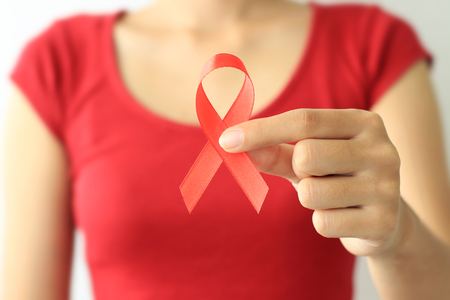 Aids Awareness. female hands holding red AIDS awareness ribbon.