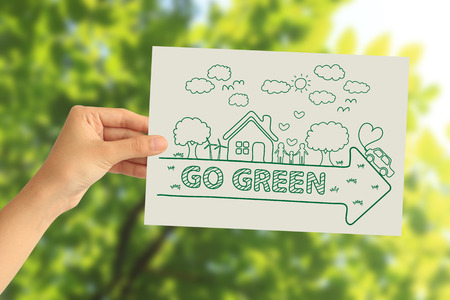 Hand holding a paper card with creative drawing ecology concept on abstract nature backgroundの写真素材