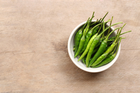 Green Pepper in a bowl on wooden table backgroundの写真素材