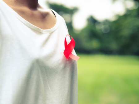 female hands holding red AIDS awareness ribbon. World AIDS Day.