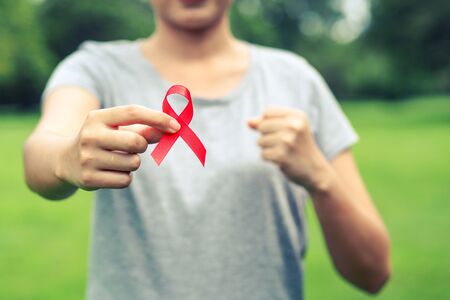 female hands holding red AIDS awareness ribbon. World AIDS Day.の写真素材