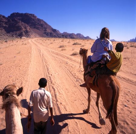 Girl on trip with camels through Wadi Rum desert in Jordanの写真素材