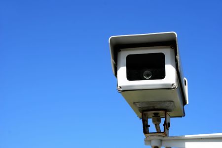 surveillance security camera against clear blue sky
