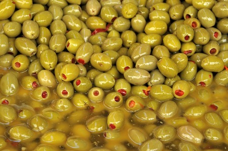 Green pitted olives with red pimento offered for sale at a farmers markeの写真素材