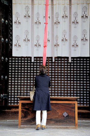 Nara Japan-November 6, 2014; Lady praying and ringing the bell at the Eastern Golden Hall of...