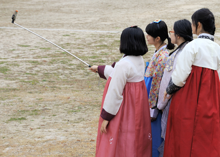 Seoul, South Korea-November 10, 2015; Girls in traditional costume taking a selfie on a mobilephone in midtown Seoul.のeditorial素材