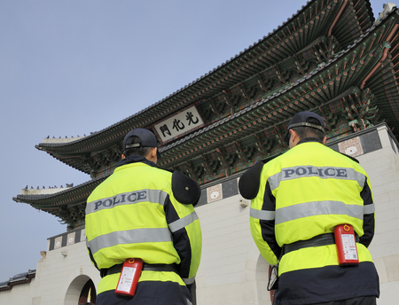 Seoul, South Korea-November 11, 2015; Two policemen seen from the back standing in front of the Gyeongbokgung Royal Palace. November 11, 2015 Seoul, South Koreaのeditorial素材
