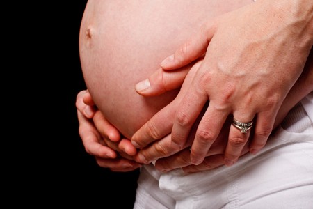 A loving couples embraced hans around an expectant mother.