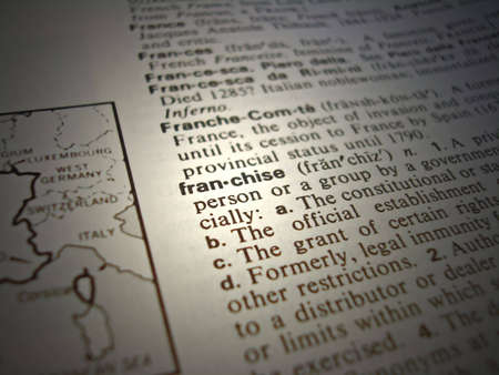 A close up of the word franchise from the dictionary.  Focus / lighting on the word franchise with intentional blurring and shadows on surrounding words.                               の写真素材