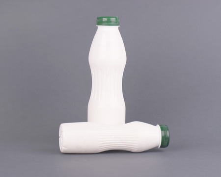 White plastic bottle with milk, yogurt or kefir, on a gray background. Mock up template design without label. Photoの写真素材