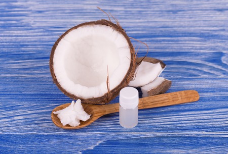 Coconut with coconut oil and milk on blue wooden background. Healthy food concept