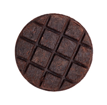 Round flat disc of puer tea isolated on white background. Chinese tea Shou Puer. Pressed fermented Pu-erh tea. Macro close up. Aromatic black puer tea. Healthy drink.の写真素材