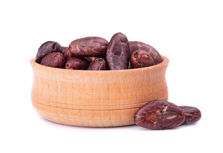 Peeled cocoa beans in the wooden bowl, isolated on white background. Roasted and aromatic cocoa beans, natural chocolateの写真素材
