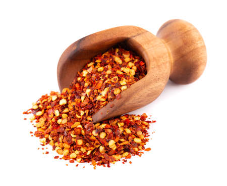 Chili and paprika in wooden scoop, isolated on white background. Mix of hot and sweet red pepper...