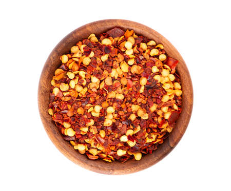 Chili and paprika in wooden bowl, isolated on white background. Mix of hot and sweet red pepper with...