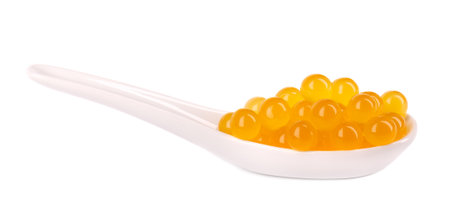 Yellow tapioca pearls for bubble tea isolated on white background. Tapioca pearls in ceramic spoon.の写真素材