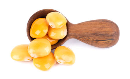 Pickled yellow lupine beans in wooden spoon, isolated on white background. Tournus, preserved lupinus.の写真素材