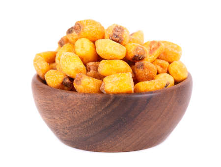 Roasted salted corn nuts in wooden bowl, isolated on white background. Beer snack, dry corn with spices.の写真素材
