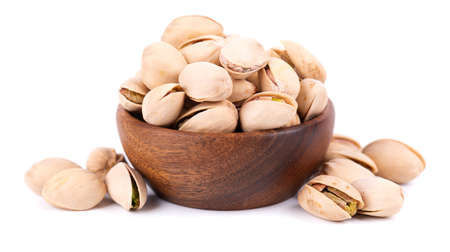 Pistachio nuts, isolated in wooden bowl, on white background. Salted roasted pistachios.の写真素材