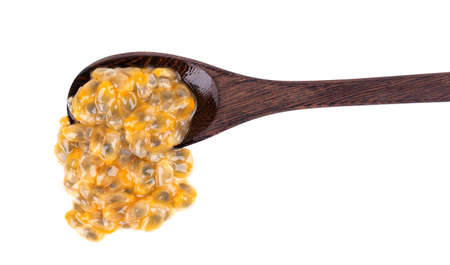 Passion fruits seeds in wooden spoon, isolated on white background. Passionfruit or maracuya pulp, exotic fruit.の写真素材