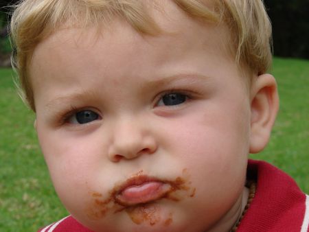  boy eating chocolate outsideの写真素材
