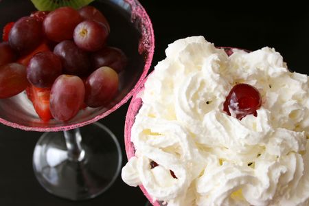 Cherry and cream on top of a fruit salad in glassesの写真素材