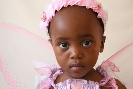 Toddler girl in a pink fairy costume with wings and head pieceの写真素材