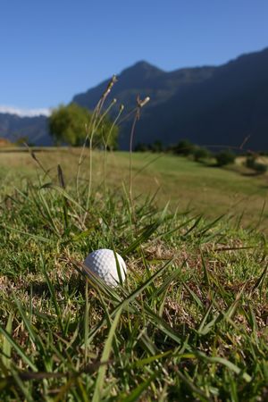 Golf Ball on a golf course with a mountain range in the backgroundの写真素材