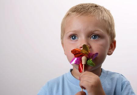 Toddler playing with a wind toy made of bright colorsの写真素材