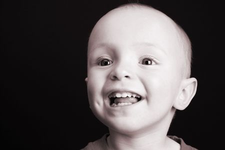 Blonde toddler against a black background with a big smileの写真素材