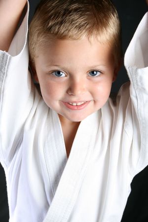 Young boy wearing his karate uniform on a black backgroundの写真素材