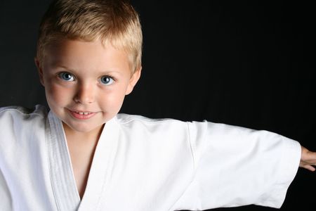 Young boy wearing his karate uniform on a black backgroundの写真素材