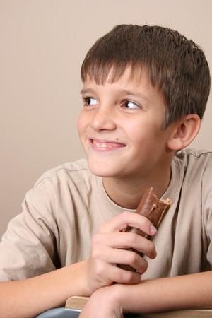 Young boy with big eyes, eating a chocolate barの写真素材