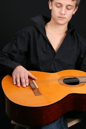 Teenage male in casual attire holding a guitar. FOCUS ON GUITAR by HAND