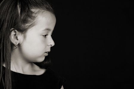 Serious little brunette girl against a black backgroundの写真素材