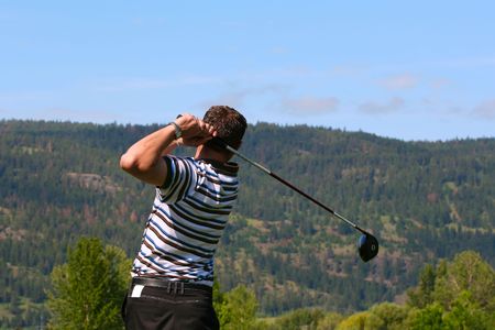 Young golfer following his ball after teeing offの写真素材