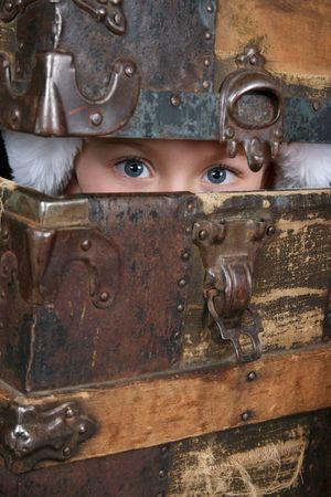 Beautiful blue eyed boy peeping from within an antique trunk