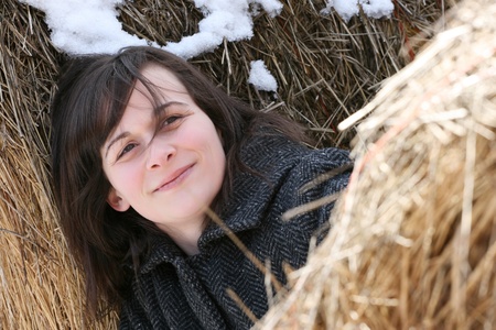 Beautiful brunette female leaning against hay balesの写真素材