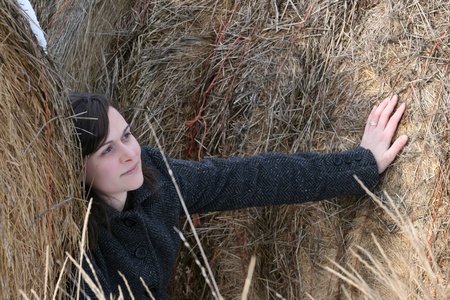 Beautiful brunette female leaning against hay balesの写真素材