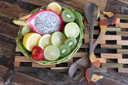 Fruit basket on wooden placemat with ornate spoonsの写真素材