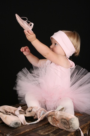 Blond toddler wearing a tutu holding Ballet shoes の写真素材